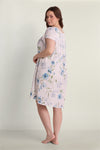 Woman wearing a light pink short nightgown with blue floral print, shown from the back in a three-quarter view.