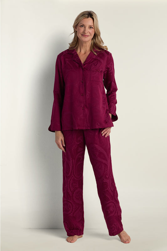 Woman wearing burgundy brushed back satin pajama set with long sleeves and full-length pants, front view.