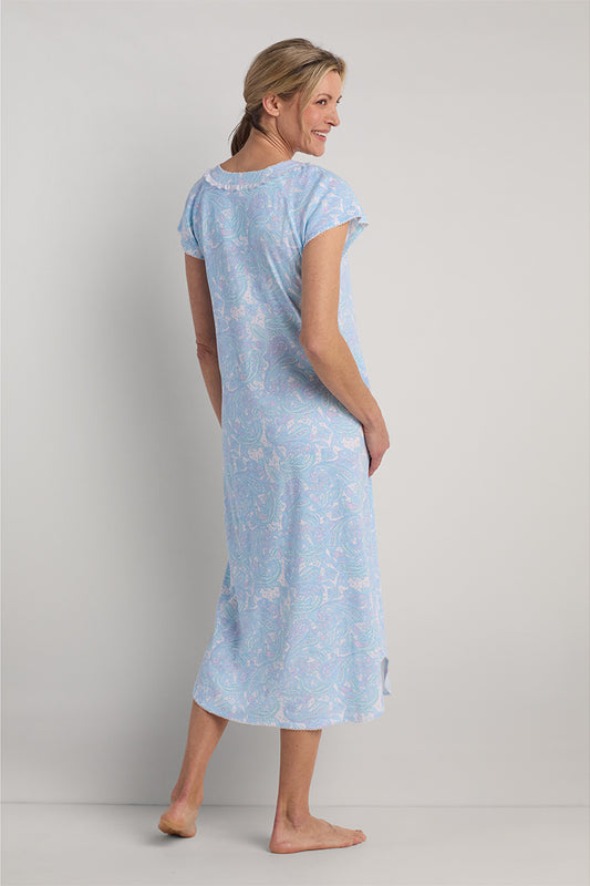 Woman wearing a light blue paisley long nightgown with short sleeves, shown from the back view.