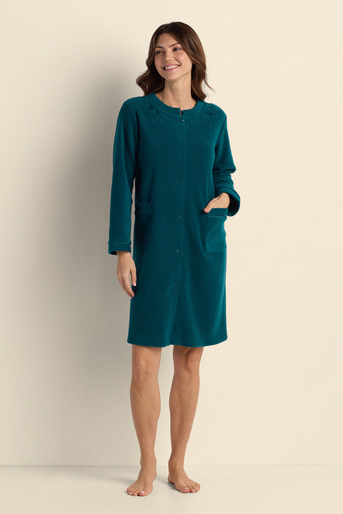 Teal fleece short robe with long sleeves and front button closure, worn by woman standing against neutral background.