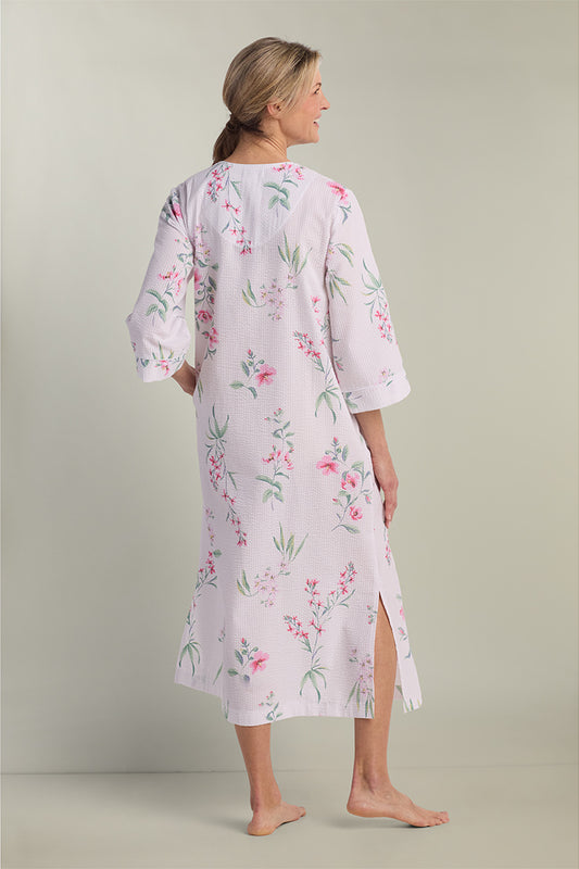 Woman wearing lavender floral seersucker long robe with three-quarter sleeves, shown from back view.