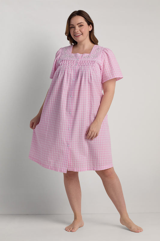 Pink and white seersucker short robe with short sleeves and smocked neckline, front view on model.