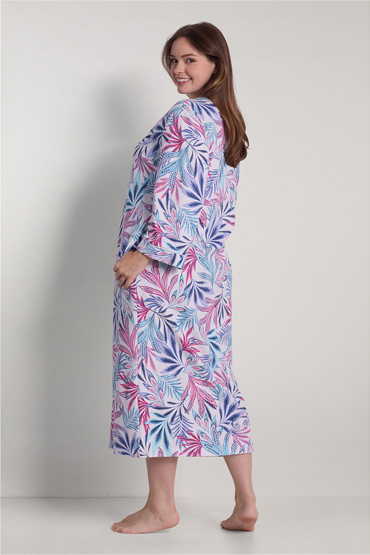 Woman wearing a long robe with purple, pink, and blue leaf pattern, shown from the side view.