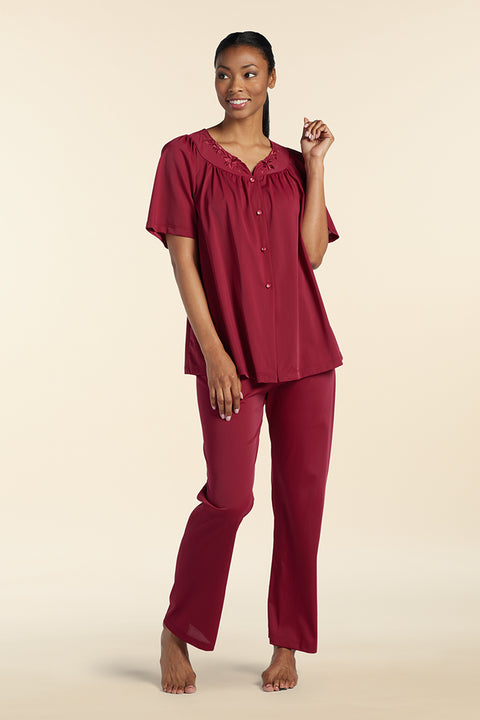Woman wearing burgundy nylon tricot short-sleeve pajama set with button-front top and straight-leg pants, standing barefoot